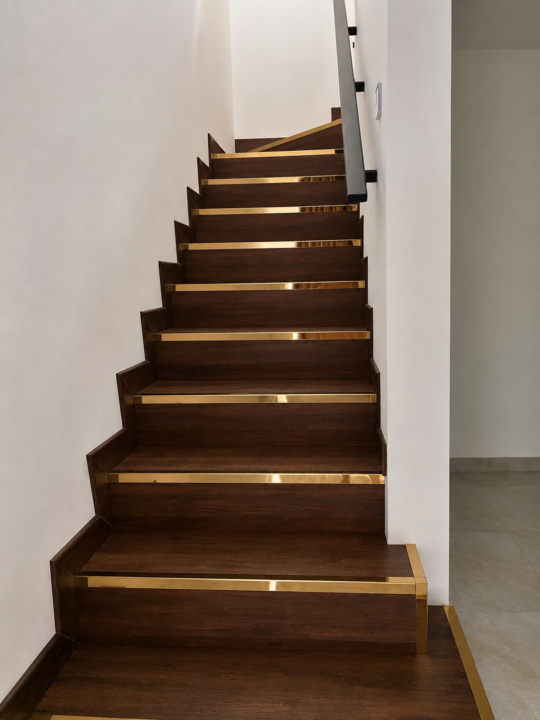 Dark brown wooden staircase with gold trim along every step
