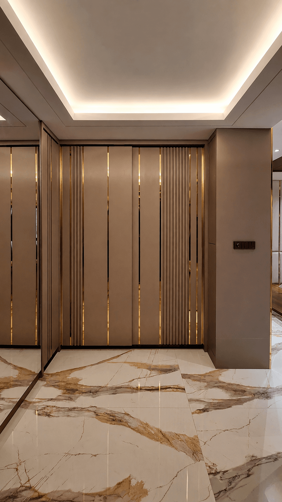 Corridor with light brown wall panels in vertical gold stainless trim, on white marble floors veined with gold